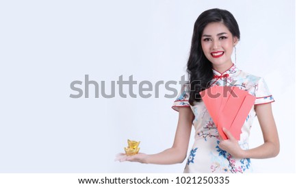 Portrait of beautiful asian woman in white chinese dress traditional cheongsam. chinese new year concept.Smiling Chinese woman is holding red packet of Ang Pao and gold present of Chinese New Year. 