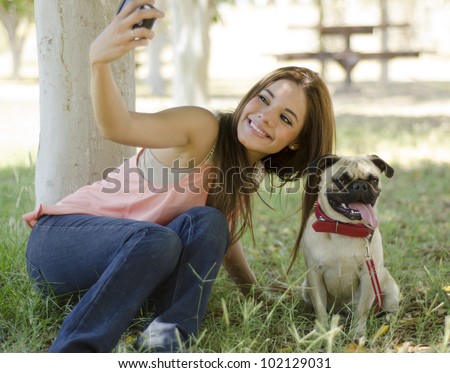 Beautiful latin woman taking a picture with her dog at the park