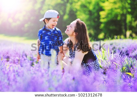 Happy mom with cute son on lavender background. Beautiful woman and boy in meadow field. Lavender landscape with lady and kid enjoying aroma and vivid colors. Best photo for 8 march, women day.
