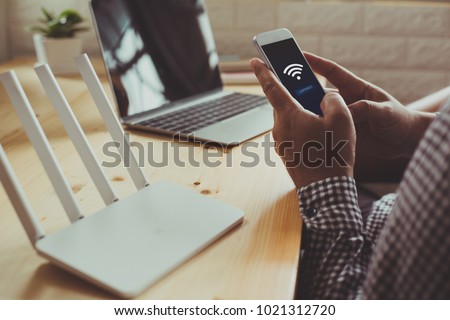 closeup of a wifi router and a man using smartphone on living room at home ofiice Royalty-Free Stock Photo #1021312720
