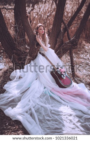 Beautiful romantic european girl with guitar with flowers inside, posing outdoors. Concept of music and nature. Spring time. Fashion retouched shot