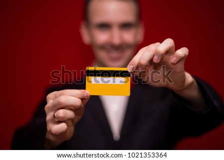 Stylish man in suit hold credit card, with red background, focus on credit card. Payment concept