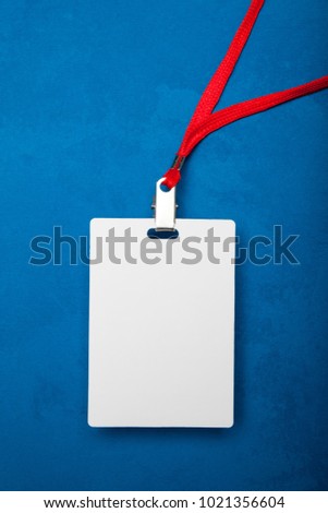 Blank identification card with red neckband isolated on blue background.