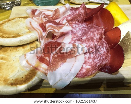 This is a photo of an Italian food. It has raw meat with bread and cheese. A meat are called salami. It is tasty and delicious.