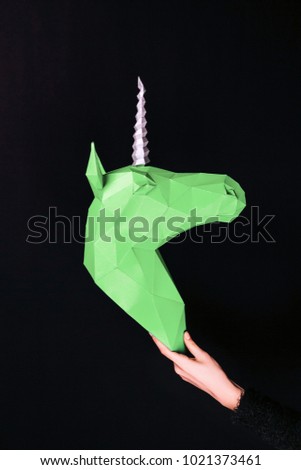 Hands hold a green Unicorn. Artwork. 3d papercraft model of a unicorn. Copy space