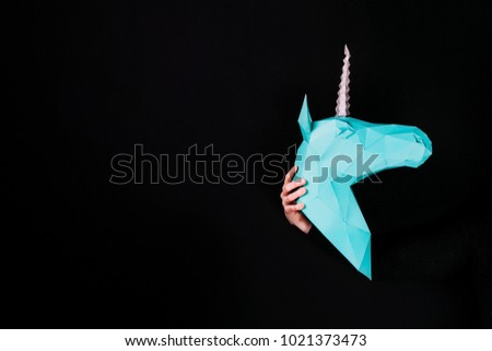 Hands hold a turquoise Unicorn. Artwork. 3d papercraft model of a unicorn. Copy space