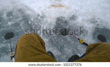 Winter fishing rods on the ice near fishing hole and fisherman's legs. Suitable for any purpose use