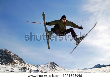 Jumping alpine skier against the blue sky in mountains