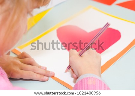 Child draw a postcard. Children are engaged in needlework. The girl signs a postcard on 14 February. St. Valentine's Day.