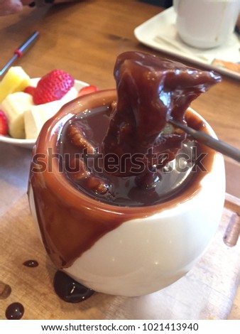 Chocolate fondue with fruits served wooden in a restaurant, vertical picture