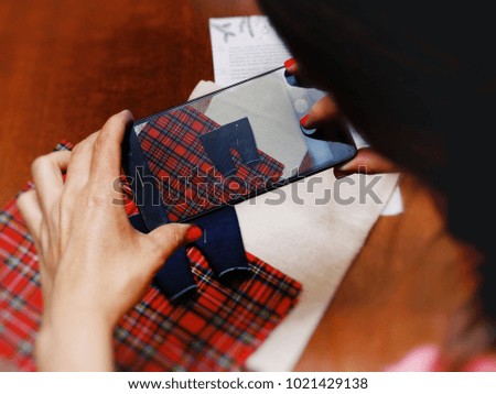 Woman Photographs on Smartphone sewn clothes for Dolls. Home business concept.