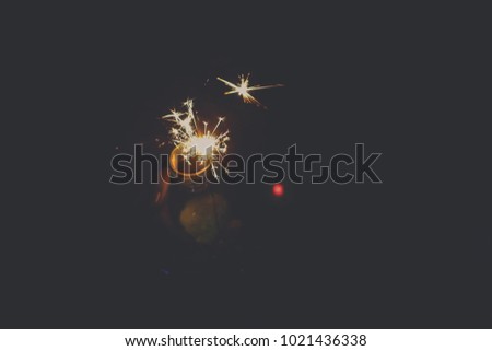 Funny Abstract blur sparklers for celebration background,Motion by wind blurred woman hand holding glass bottle burning Christmas sparkle  and dark night background.Vintage flim grain style.