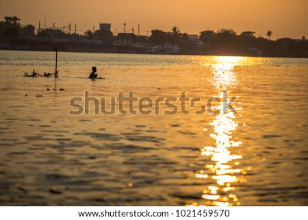 Silhouette of asian fisherman ,fisherman in action throwing a net for catching freshwater fish in nature river, traditional fishermen at the sunset near Galle in Chao phrya river thailand