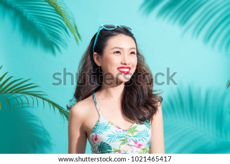 Summer fashion girl standing and smiling over vibrant blue background