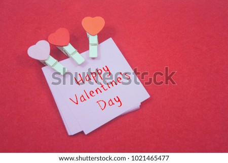 wooden clips with note paper written happy valentine's day isolated on red background