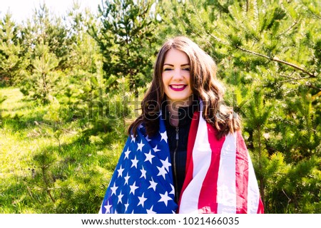 A young beautiful woman with a flag of the United States of America.Smiles