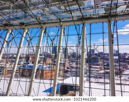 View of downtown area of Kansas City after a snowfall through tall glass windows of a large building; Kansas City, MO