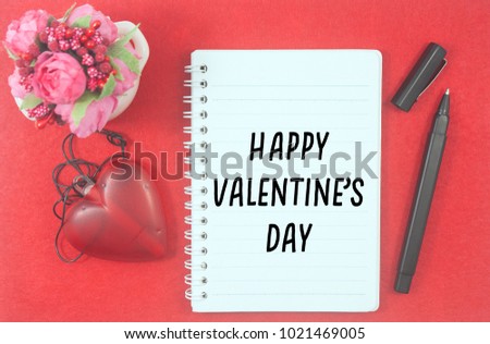 Glow heart pendant necklace,pens,artificial bonsai and notebook written happy valentine's day over red background