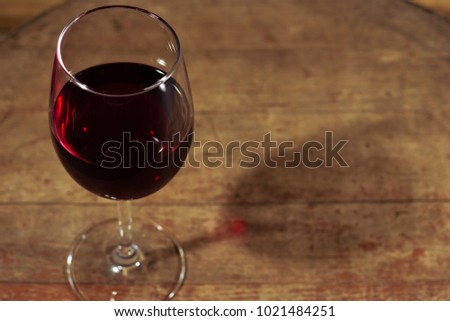 Glass of wine A black bottle of red wine on a wooden table. Beautiful dark background