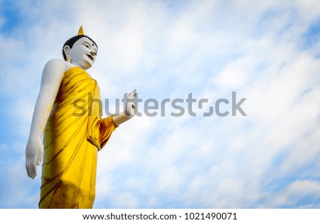 Standing Buddha under blue sky background with cloud.