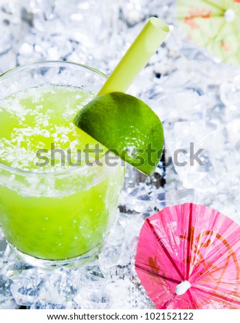 Fresh delicious lime smoothie on a bed of crushed ice with a cocktail umbrella