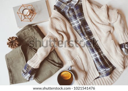 cozy autumn woman casual outfit set flat lay. Plaid shirt, knitted sweater, blue cross body bag  and khaki pants on white background. Stylish fashion, top view.