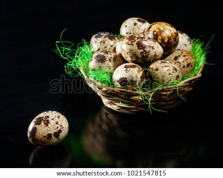 A wicker bowl with quail eggs on a dark background.