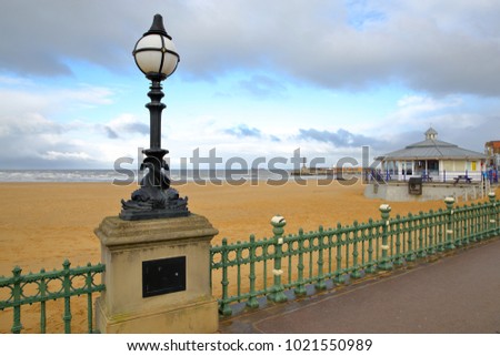The Margate seafront with a designed street lamp in the foreground and Margate Harbor Arm in the background, Margate, Kent, UK Royalty-Free Stock Photo #1021550989