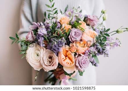 Very nice young woman holding big and beautiful colourful flower wedding bouquet with purple carnations and mattiolas, cream David Austin roses, ranunculus and pistachios Royalty-Free Stock Photo #1021598875