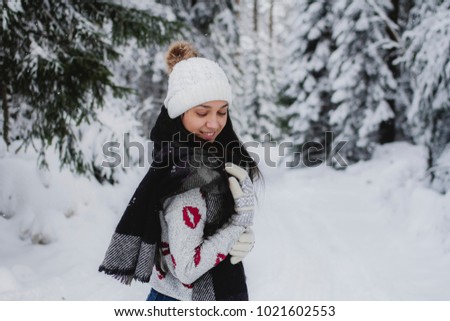 Portrait of a beautiful girl in winter clothes in the forest, the girl smiles with closed eyes