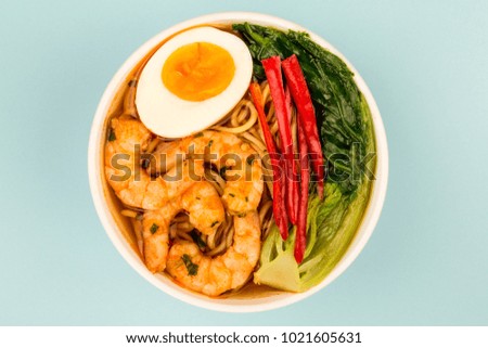 Japanese Style Prawn And Noodle Ramen Soup With Pak Choi And Chillies Against A Light Blue Background