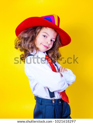 Happy child wearing bright colorful hat on yellow background