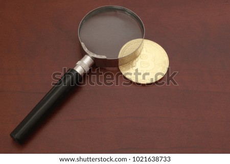 Magnifying glass and golden bitcoin 