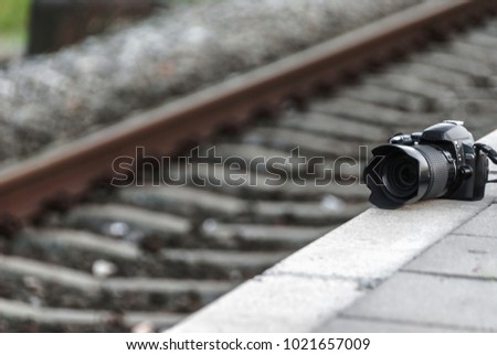 Nikon camera placed on a side walk next to a rail-road track