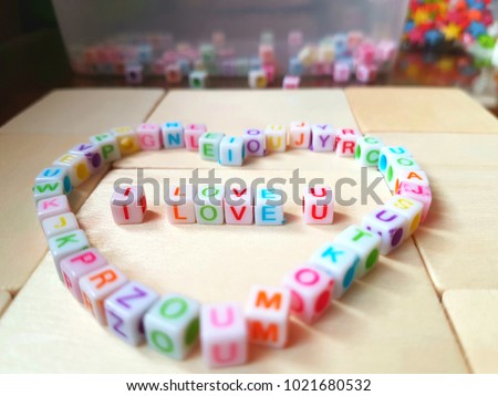 colorful cube-shaped plastic letters put in the words "I LOVE U" on the wooden board , selective focus