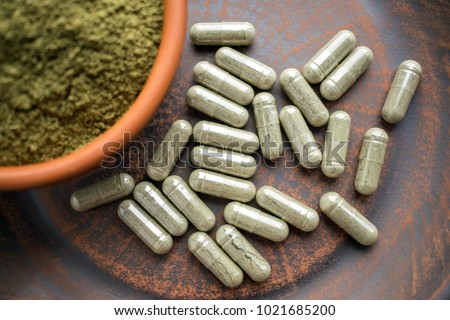 Close up Green capsules and powder on a clay brown plate on a burlap rustic background. Dietary supplements, vitamins and minerals for vegans and vegetarians. Healthy lifestyle, superfood Royalty-Free Stock Photo #1021685200