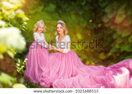 Charming princess in pink dress and tiara on a sunny green park