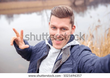 selfie of handsome blond man in front of lake in the cold