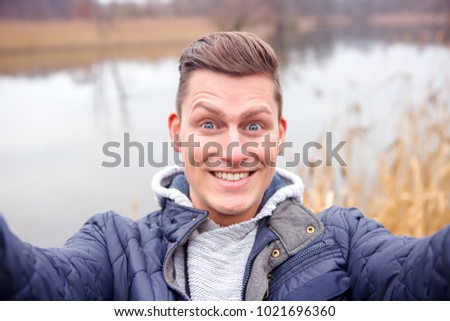 selfie of handsome blond man in front of lake in the cold