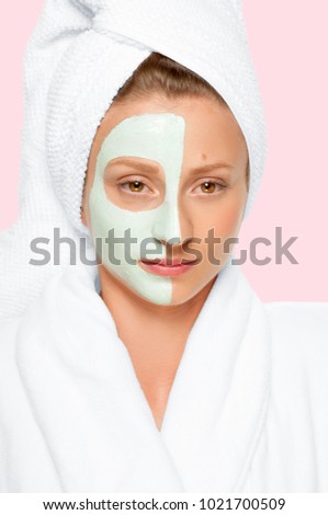 Treatment in spa salon. Beautiful young woman with cosmetic clay mask on face. Faded pastel color