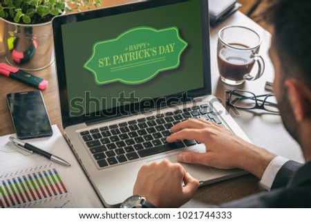 Happy St Patricks Day on computer screen, man working, office background