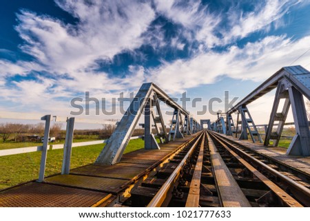 Old railroad and iron bridge structure in Europe, profiled on blue sky with clouds