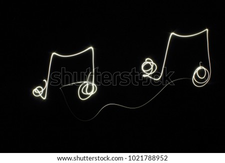 Music notes on black background created by using freeze light effect.