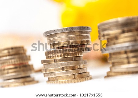closeup of euro coins piles and bank notes with yellow piggy bank on white background