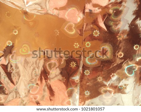 Holographic foil texture. Abstract heart shaped lights coming from the holographic foil. Good for Valentines Day celebrations. Abstract background  of Yellow, Brown, White and Red. 