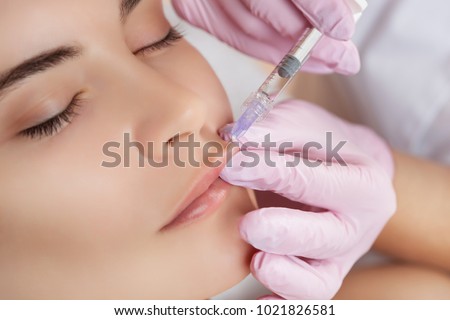 The doctor cosmetologist makes Lip augmentation procedure of a beautiful woman in a beauty salon.Cosmetology skin care. Royalty-Free Stock Photo #1021826581