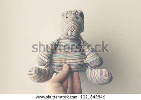Hand of the young man holding the handmade plush rabbit. Childhood concept.