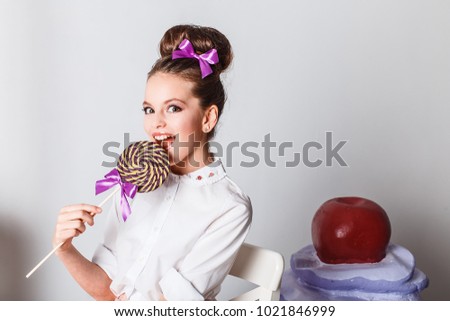 Beautiful teenage girl in pink tutu or tulle skirt with colorful purple lollipop in studio on white background isolated