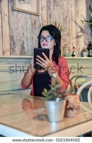 Businesswoman using tablet in cafe. Young woman working on a project.
