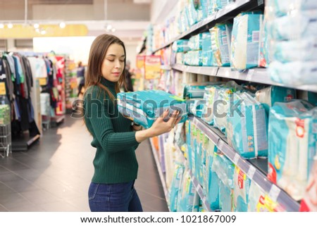 Pregnant woman buys diapers at the supermarket, portrait of young happy mother in shop mall Royalty-Free Stock Photo #1021867009
